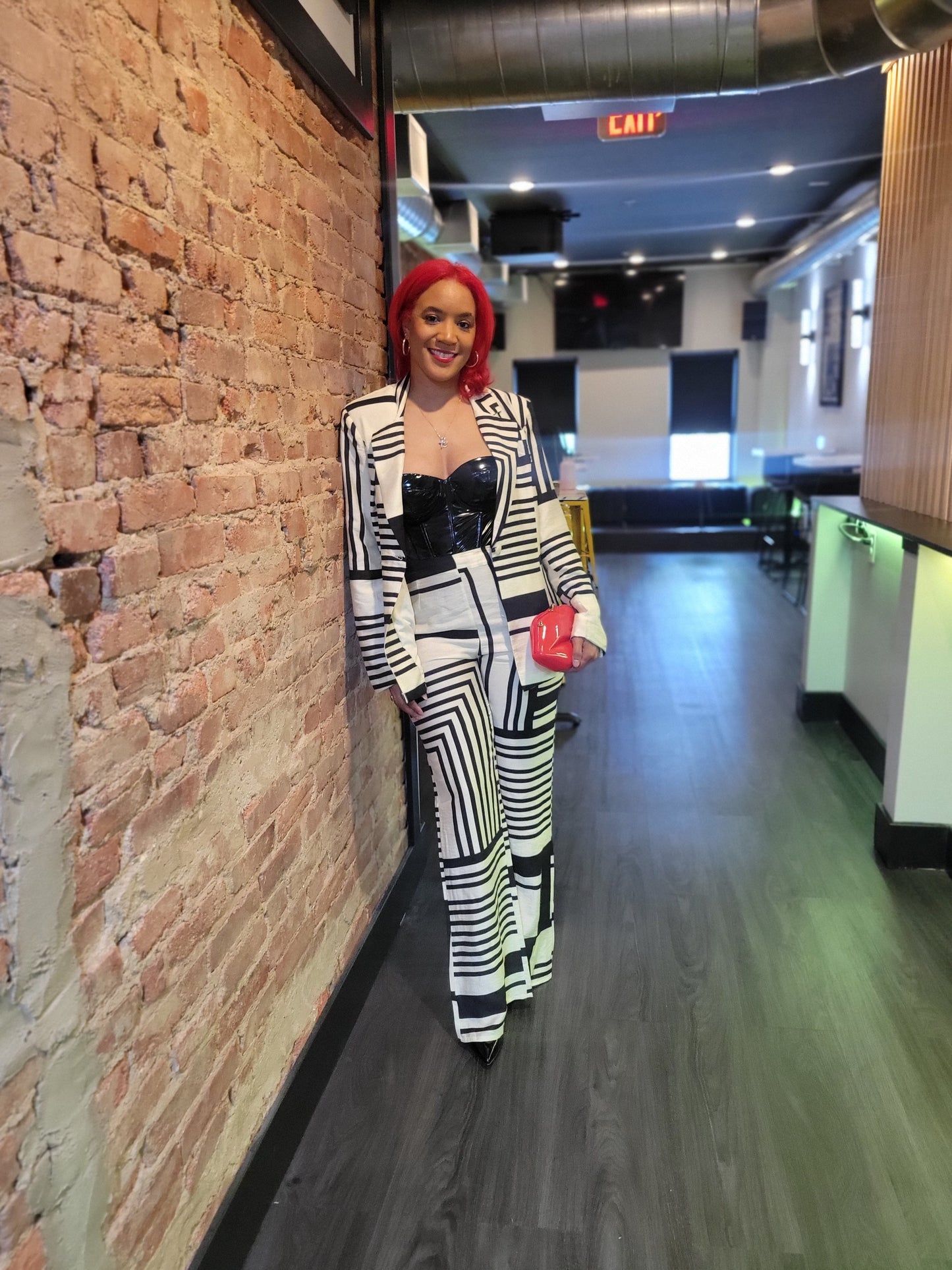 A slender woman modeling a black and cream geometric patterned pantsuit with a tailored blazer and bootcut slacks.