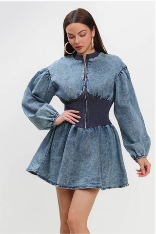 A woman wearing a Vintage style Jean Dress with a fitted waist, puff sleeves, and a zip-up front.