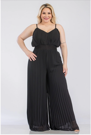 A woman wearing a pleated, plus sized black jumpsuit with a sweetheart neckline.