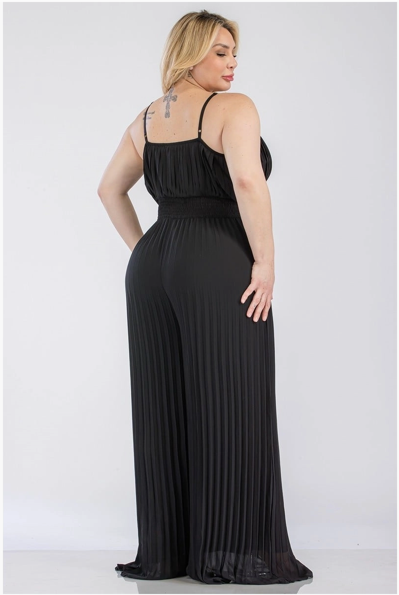 The back of a woman wearing a pleated, plus sized black jumpsuit with a sweetheart neckline.