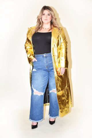 Plus sized woman wearing gold colored trench  jacket with a distressed jeans. 