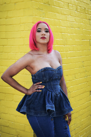 Woman wearing a denim bustier with a peplum waist.