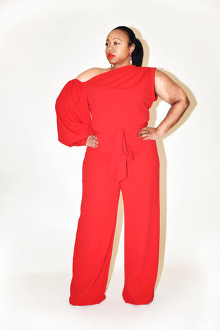 Plus sized woman wearing a red, one sleeved jumpsuit. 