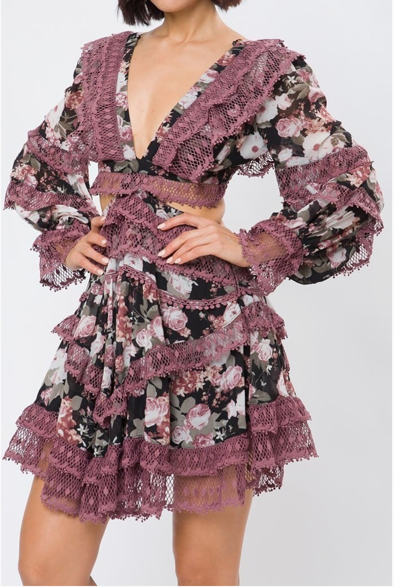A floral lace dress with long sleeves and a plunging neckline, featuring intricate lace detailing and tiered ruffles.
