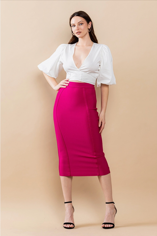 A woman wearing a magenta pink high-waisted midi pencil skirt with a white blouse.