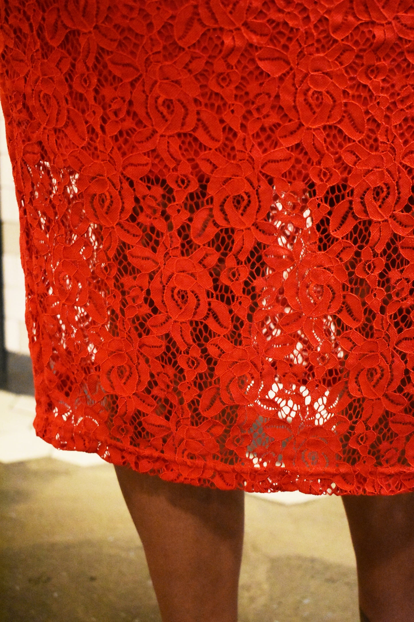 The details of a midi length red lace skirt.