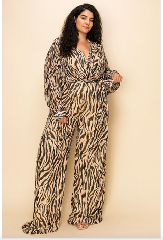 Woman wearing a tan and brown zebra print long-sleeved jumpsuit that's synched at the waist with a bow.