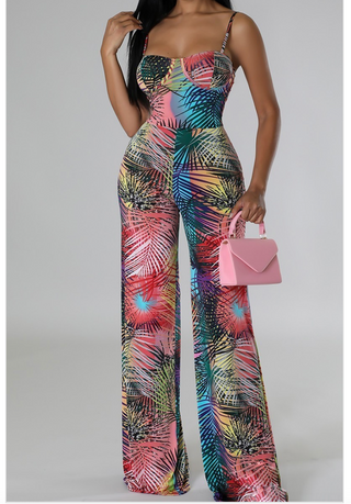 A woman wearing a vibrant, multicolor tropical print jumpsuit with a form-fitting bodice and wide-leg pants.