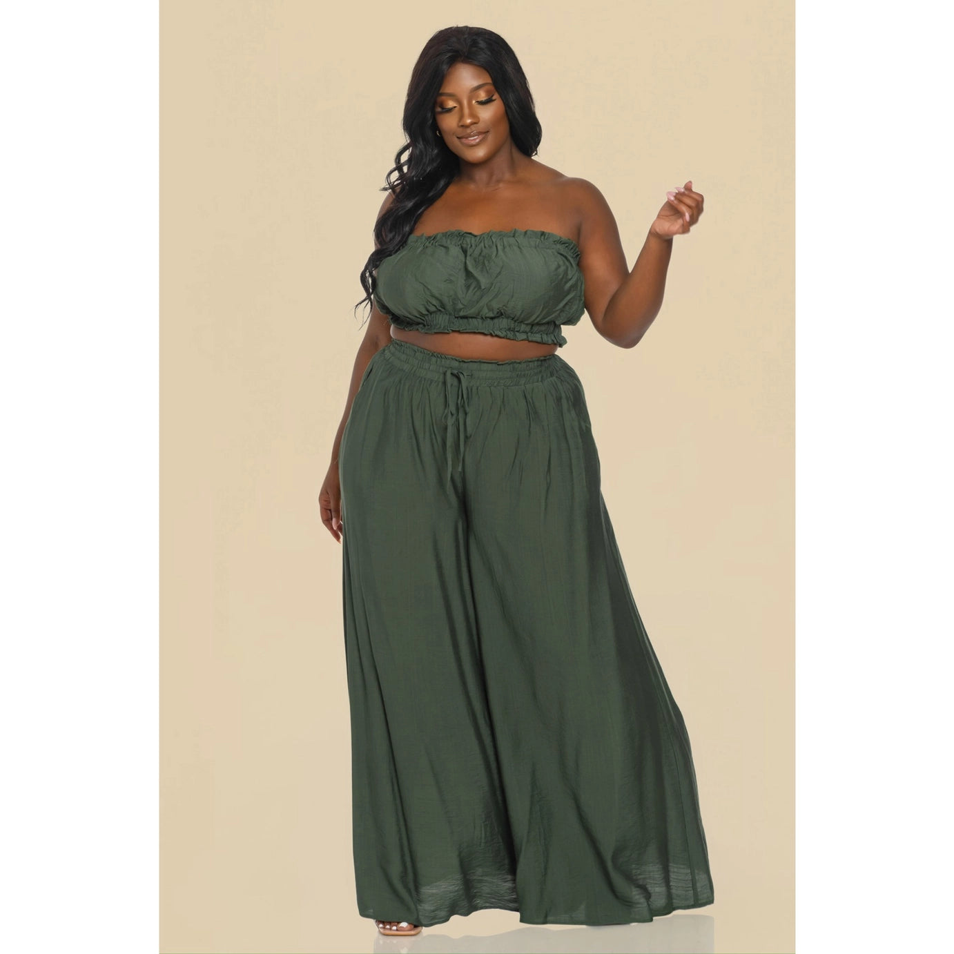 A plus sized woman wearing a sage green tube top and matching wide-leg pants.
