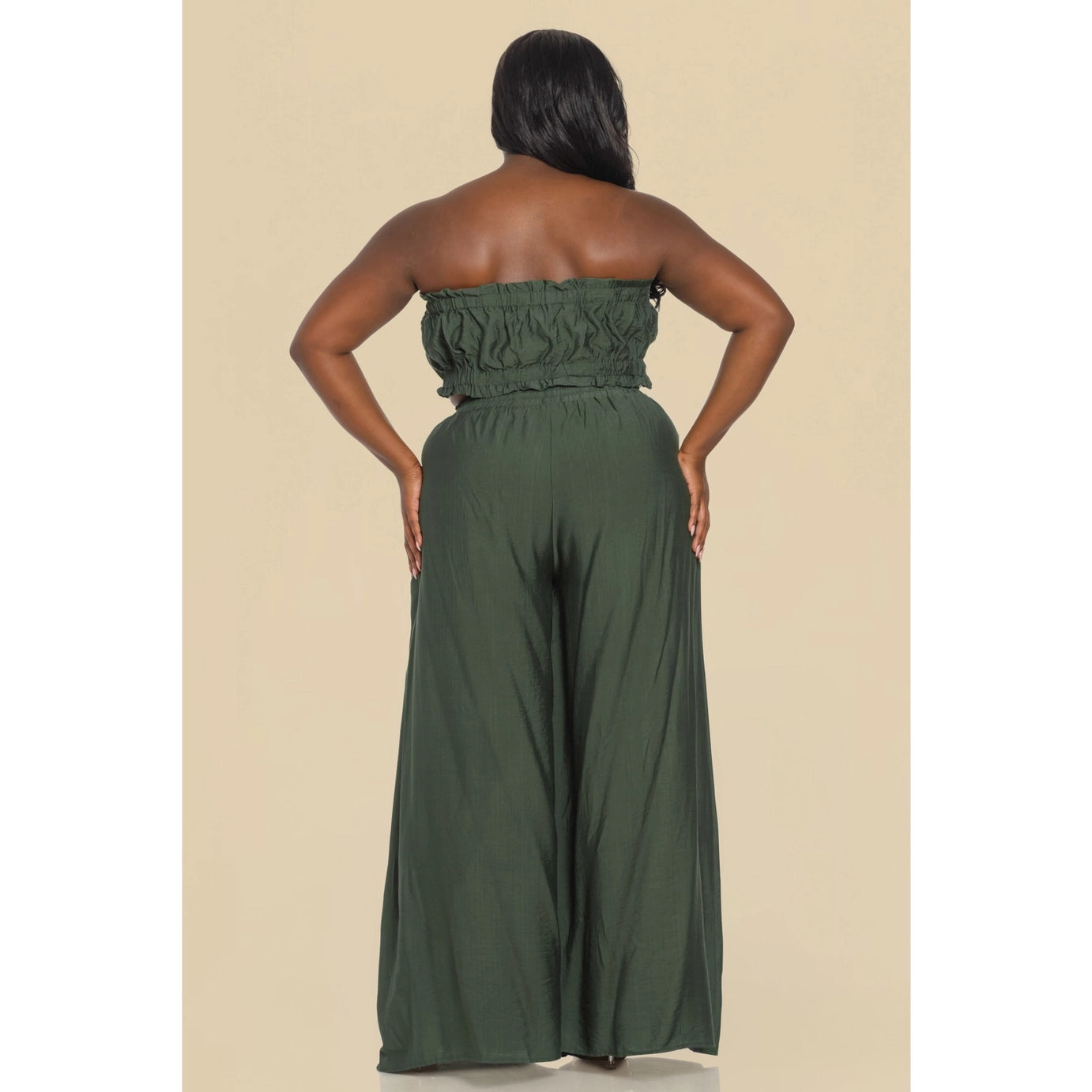 A plus sized woman wearing a sage green tube top and matching wide-leg pants.