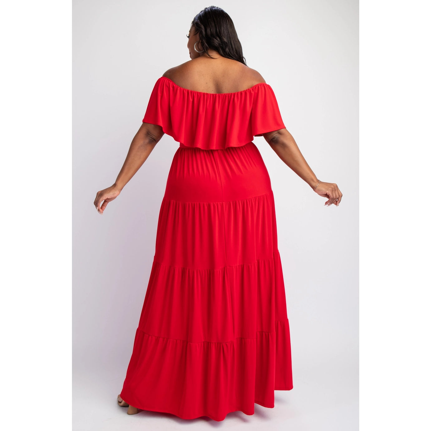 The back of a plus sized woman wearing a red, off-the-shoulder, maxi dress with ruffled sleeves and a tiered skirt. 