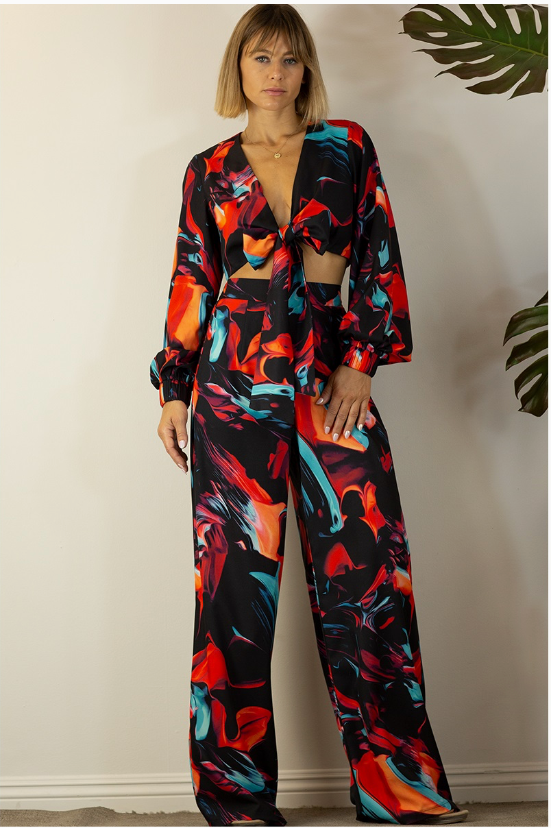 A woman wearing a multicolored pants set with a wrap crop top and straight-leg pants. 