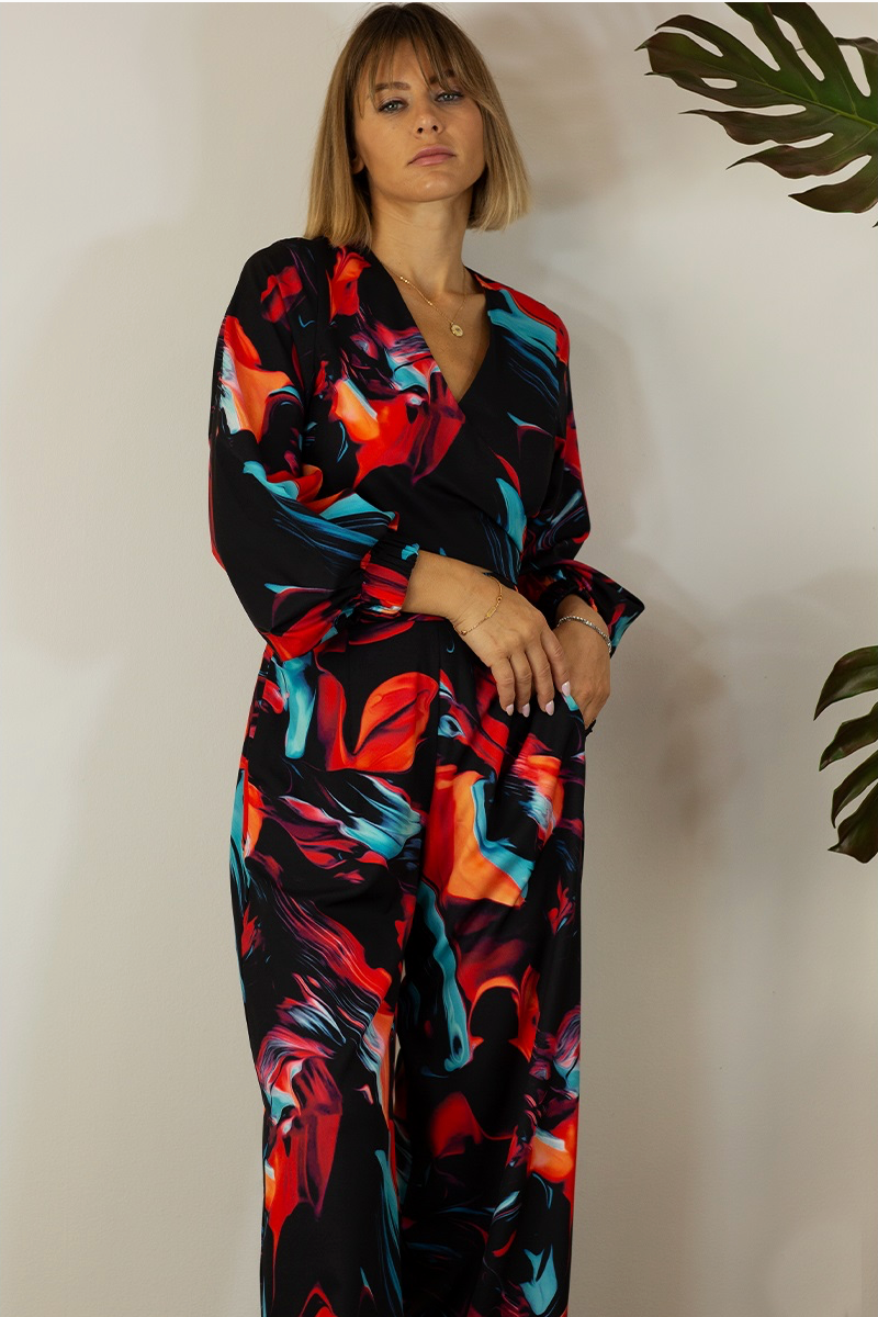 A close up of a woman wearing a multicolored pants set with a wrap crop top and straight-leg pants. 