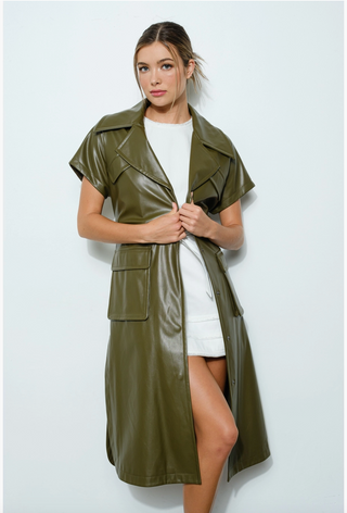 A woman wearing a green vegan leather jacket with short sleeves and oversized lapels, paired with a white dress.