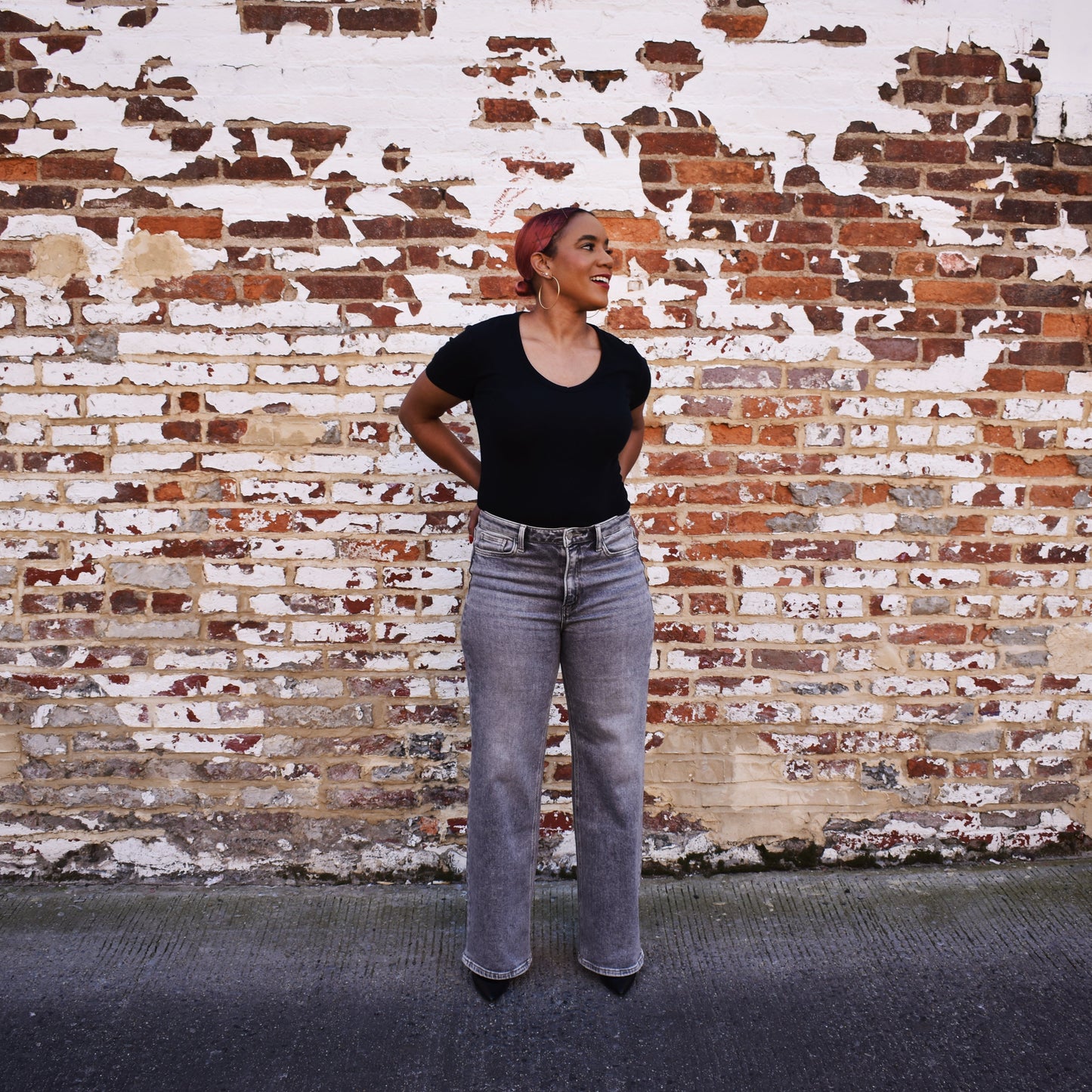Woman wearing The Olivia - Grey Wide Leg Jeans in front of a brick wall.
