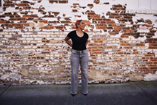 Woman wearing The Olivia - Grey Wide Leg Jeans in front of a brick wall.