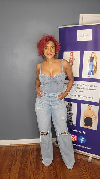 A woman wearing denim bodysuit and a pair of light blue jeans with slits in the knees.