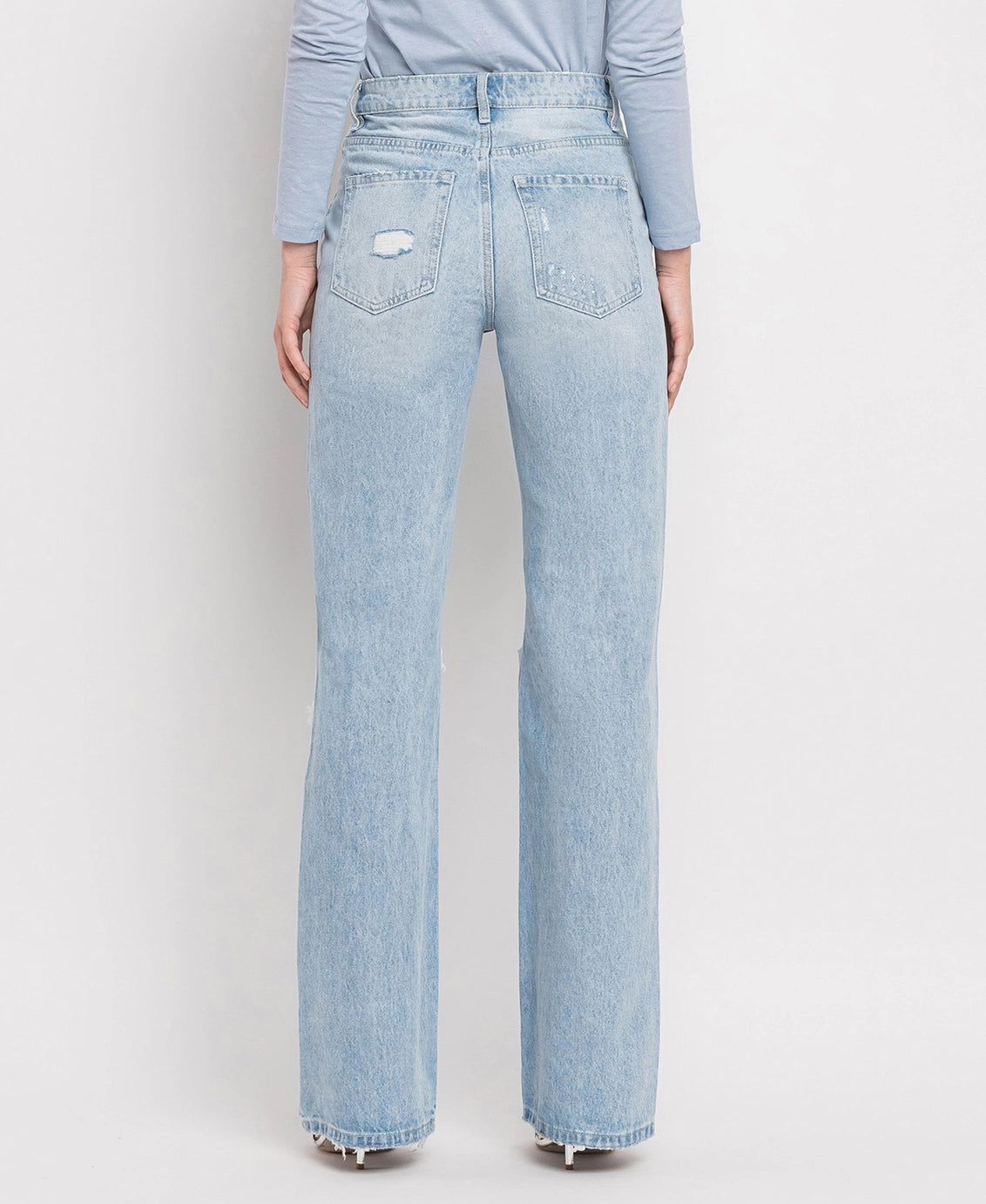 Back of a woman wearing light blue distressed straight leg jeans with slight distressing on the back pockets.